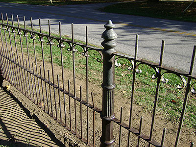 A fence made of vertical metal bars, with alternating long and short bars.