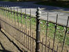 A fence made of vertical metal bars, with alternating long and short bars.