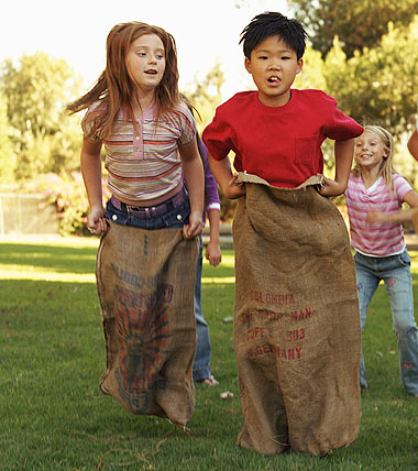 A girl and a boy participating in a sack race at a sports day.