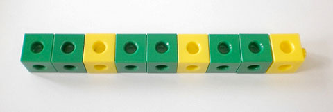 A row of cubes, made up of three groups of green-green-yellow cubes.